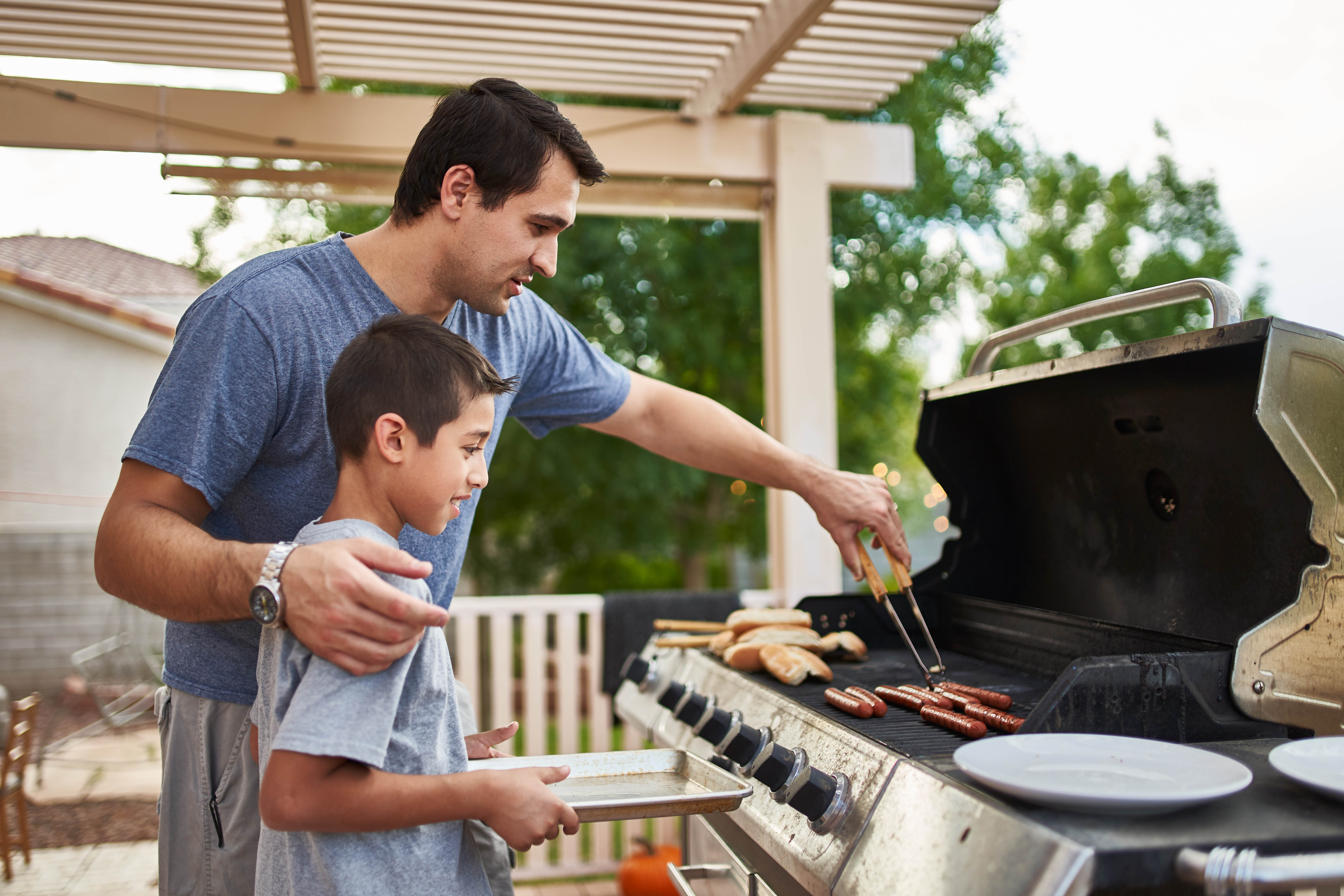 Dad getting food off the barbecue for his young son Dad getting food off the barbecue for his young son